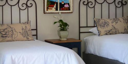 a bedroom with two beds and a vase with a plant at Dancing River Guesthouse in Vereeniging