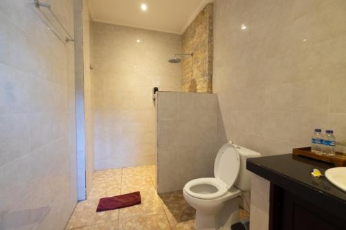 a bathroom with a toilet and a shower and a sink at Jiwa's House in Ubud
