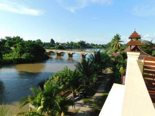 a bridge over a river with palm trees and a bridge at Sengahloune Resort in Ban Khon