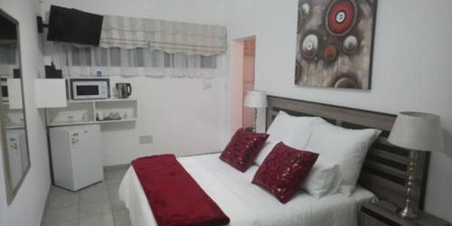 a bedroom with a large bed with red pillows at Azrielle Guesthouse in Sasolburg