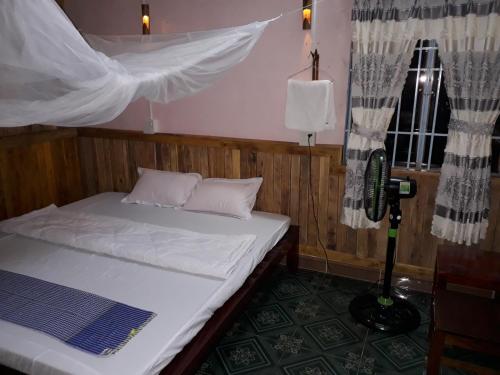 a bedroom with a bed and a window with curtains at Flower & Frog Homestay in Sa Ðéc