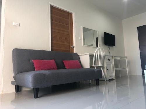 a gray couch with two red pillows in a living room at Khao Oat airport in Nai Yang Beach