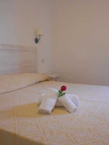 a white bed with a rose on top of it at Hotel Tabby in Golfo Aranci