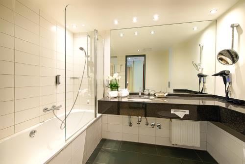 W łazience znajduje się wanna, umywalka i prysznic. w obiekcie Welcome Hotel Paderborn w mieście Paderborn