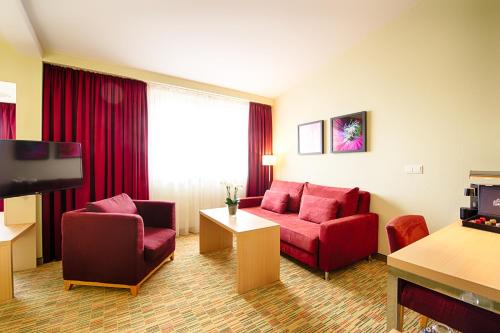 a hotel room with a red couch and chairs at Welcome Hotel Paderborn in Paderborn