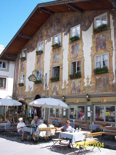 a group of people sitting at tables in front of a building at Alpenrose in Mittenwald