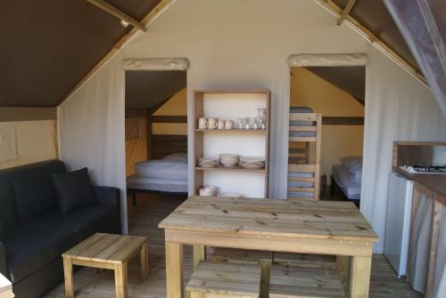 Cette chambre comprend une table, un canapé et des lits superposés. dans l'établissement Camping de Kergo, à Ploemel
