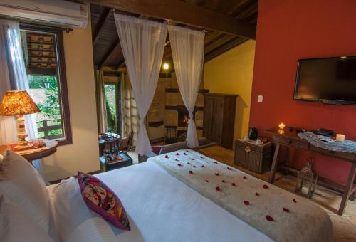 a bedroom with a white bed and a television at Estalagem Wiesbaden in Monte Verde