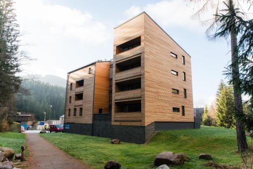 a wooden building on a hill with a grass at Apartment Mumlava Harrachov 5 in Harrachov