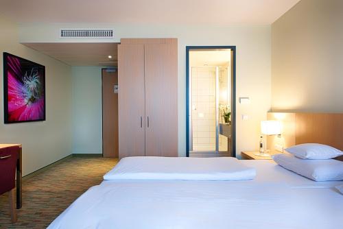 a bedroom with a large white bed in a room at Welcome Hotel Paderborn in Paderborn