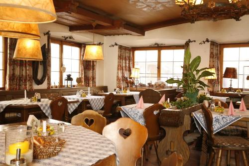 a dining room with tables and chairs and windows at Alpenrose in Mittenwald