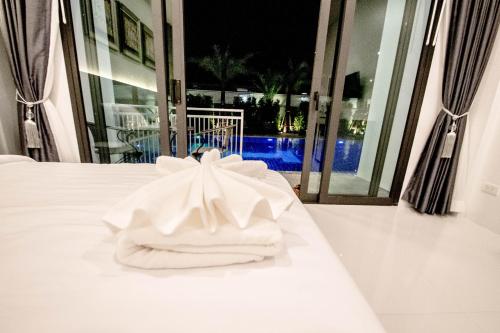 a white towel sitting on top of a bed at Baan Yamoo Ranong in Ranong