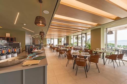 een restaurant met tafels, stoelen en ramen bij Hapimag Resort Porto Heli in Porto Cheli
