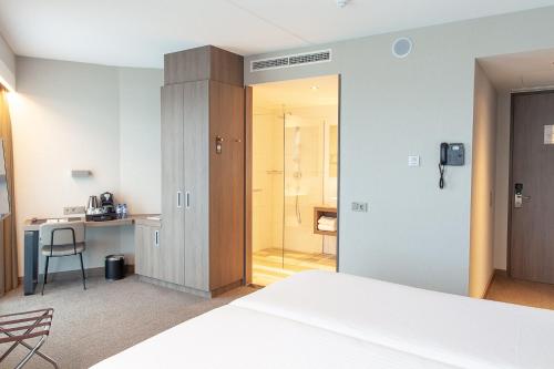 a hotel room with a bed and a desk and a bathroom at Van der Valk Hotel Groningen-Hoogkerk in Groningen