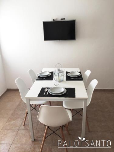 a white table with white chairs and a tv on a wall at Palo Santo Dptos. in Chilecito
