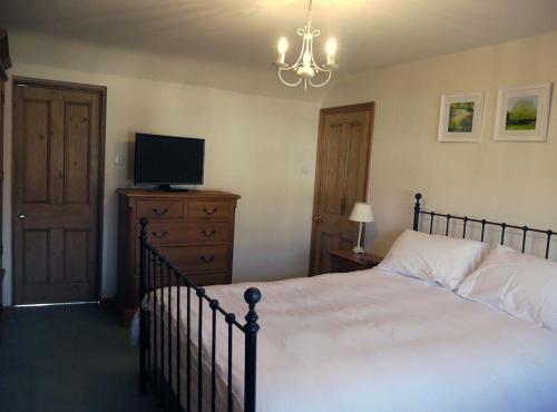 a bedroom with a bed and a tv on a dresser at One Pelham Grove Bed & Breakfast in Stocking Pelham