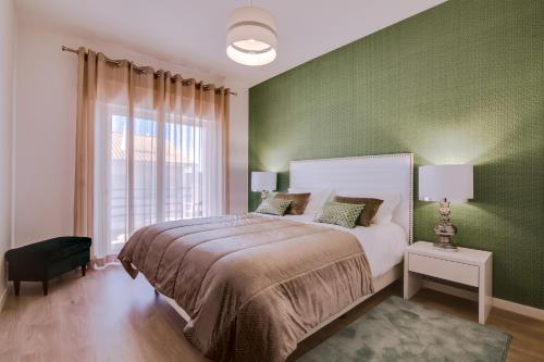 ein Schlafzimmer mit einem großen Bett und einer grünen Wand in der Unterkunft Ella - Fantastic apartment - Vilamoura in Vilamoura