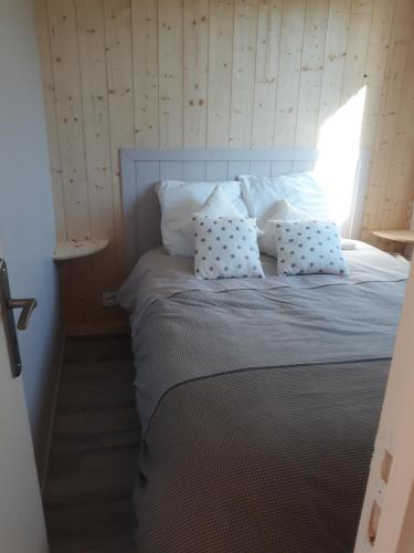 a bedroom with a bed with white pillows at Chalet "Les Gobelins" in Paimpont