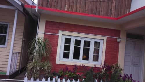 a red house with a window and a fence at Vamoose Norlha in Takdāh