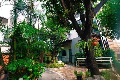 a garden with a bench and trees and a building at Bed garden 26 in Bangkok