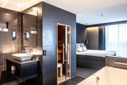 a bathroom with a bed and a sink and a tub at Van der Valk Hotel Groningen-Hoogkerk in Groningen