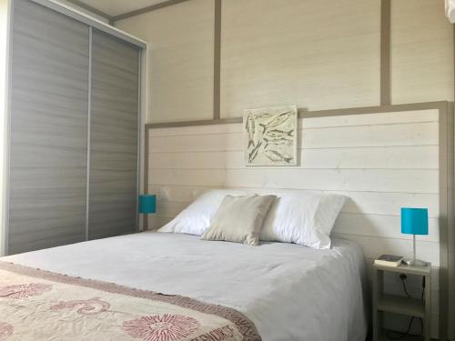 a bedroom with a large bed with white sheets and blue lamps at Les Suites De Pertamina in Bonifacio