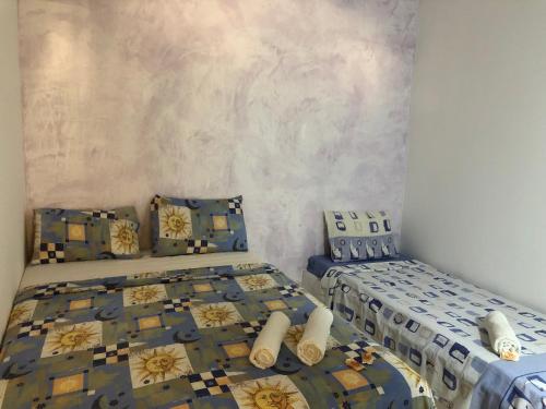 two beds in a room with blue and yellow at Pousada e Camping América in Morro de São Paulo