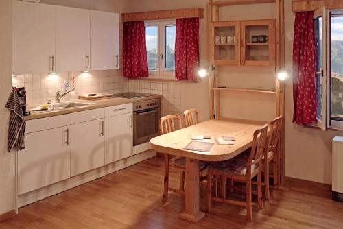eine Küche mit einem Holztisch mit Stühlen und einem Waschbecken in der Unterkunft Haus Fischer, Wohnung Grest in Flumserberg