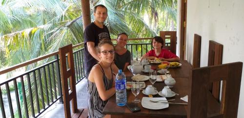 a group of people sitting at a table on a balcony at Peacock Riverside in Udawalawe