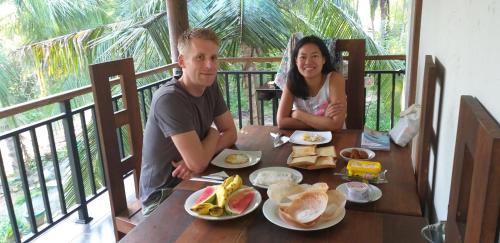 a man and a woman sitting at a table with food at Peacock Riverside in Udawalawe
