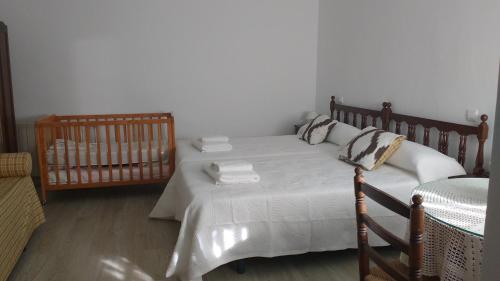 a bedroom with a bed and a crib with towels on it at Casa Fraile in Olmedilla del Campo