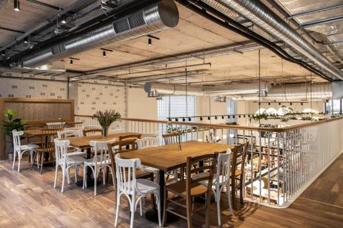 a restaurant with wooden tables and white chairs at Ergon House Athens in Athens
