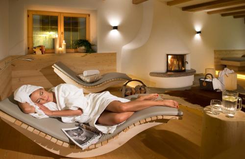 a woman laying on a bed in a living room at Sporthotel Sonne in Alpe di Siusi