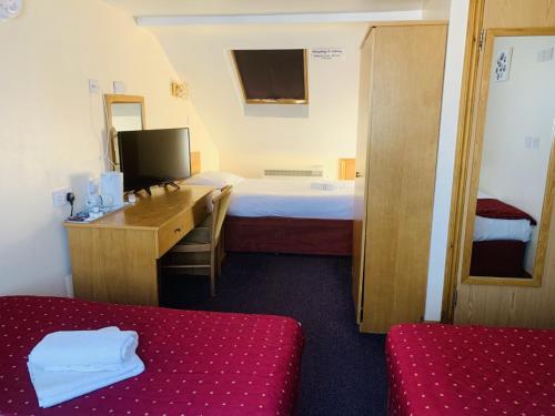 a hotel room with a bedroom with a bed and a desk at Britannia Inn Hotel in Ilford