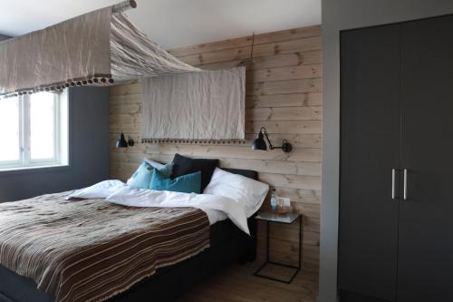 a bedroom with a bed and a wooden wall at Solsiden Brygge Rorbuer in Ballstad