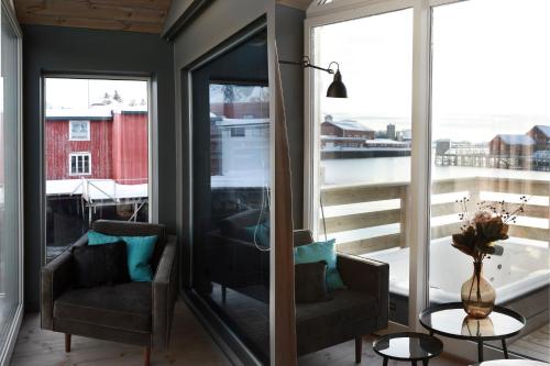 a living room with two chairs and a large window at Solsiden Brygge Rorbuer in Ballstad