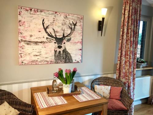 a dining room table with a deer painting on the wall at Inselferien Micheel in Burg auf Fehmarn