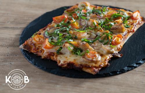 a slice of pizza sitting on a black plate at Hotel Puntarenas Beach in Puntarenas