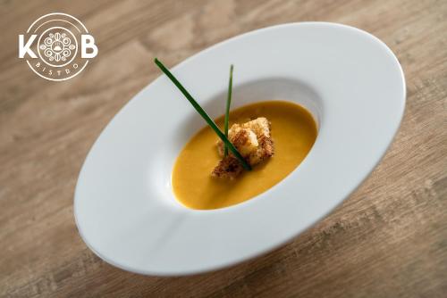 a white plate with a bowl of soup on a table at Hotel Puntarenas Beach in Puntarenas
