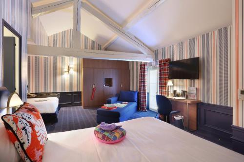 a hotel room with a bed and a living room at Hôtel du Cheval Blanc - Paris Marne La Vallée in Jossigny