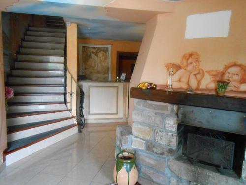 a living room with a stone fireplace and a staircase at Le Logis du Pré Braheux in Saint-Nabord