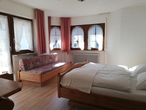 a bedroom with a bed and a couch and windows at Gästehaus Rössle in Friedenweiler-Rotenbach