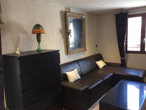 a living room with a black leather couch and a mirror at La Galisesagnoise in Briançonnet