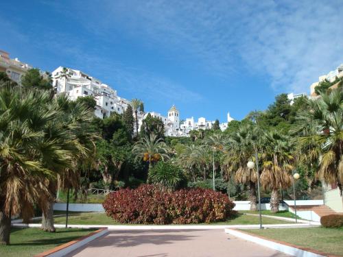 park z palmami i budynek w tle w obiekcie Capistrano Playa RELAX & ENJOY w mieście Nerja