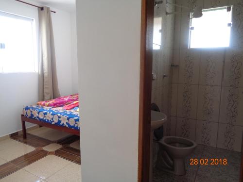 baño pequeño con cama y ducha en Pousada Bela Vista, en São Thomé das Letras