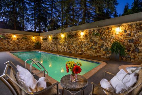 a pool with chairs and a table with a vase of flowers at Vail's Mountain Haus at the Covered Bridge in Vail