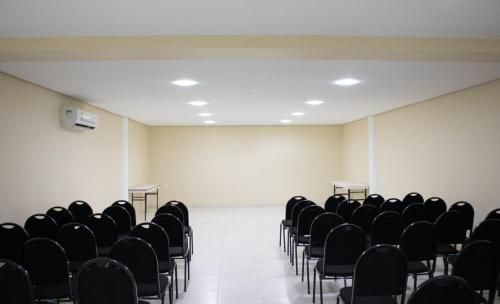 an empty room with black chairs and white walls at Fórmula Arrey Hotel - Uruçuí in Uruçuí