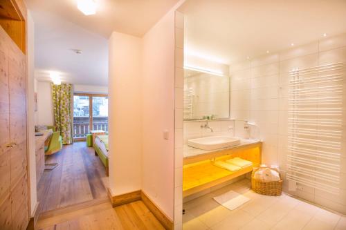 a bathroom with a tub and a sink and a mirror at Hotel Glemmtalerhof in Saalbach-Hinterglemm