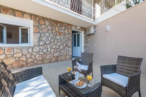 eine Terrasse mit einem Tisch, Stühlen und einer Steinmauer in der Unterkunft S & V Deluxe Apartments in Dubrovnik
