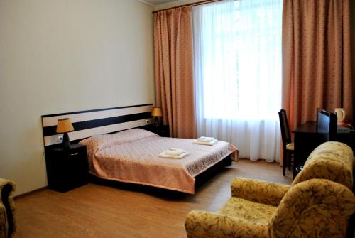 a bedroom with a bed and a chair and a window at Elegia Hotel in Kharkiv